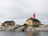 Einige Felsen, ein Leuchturm und drei Häuser.